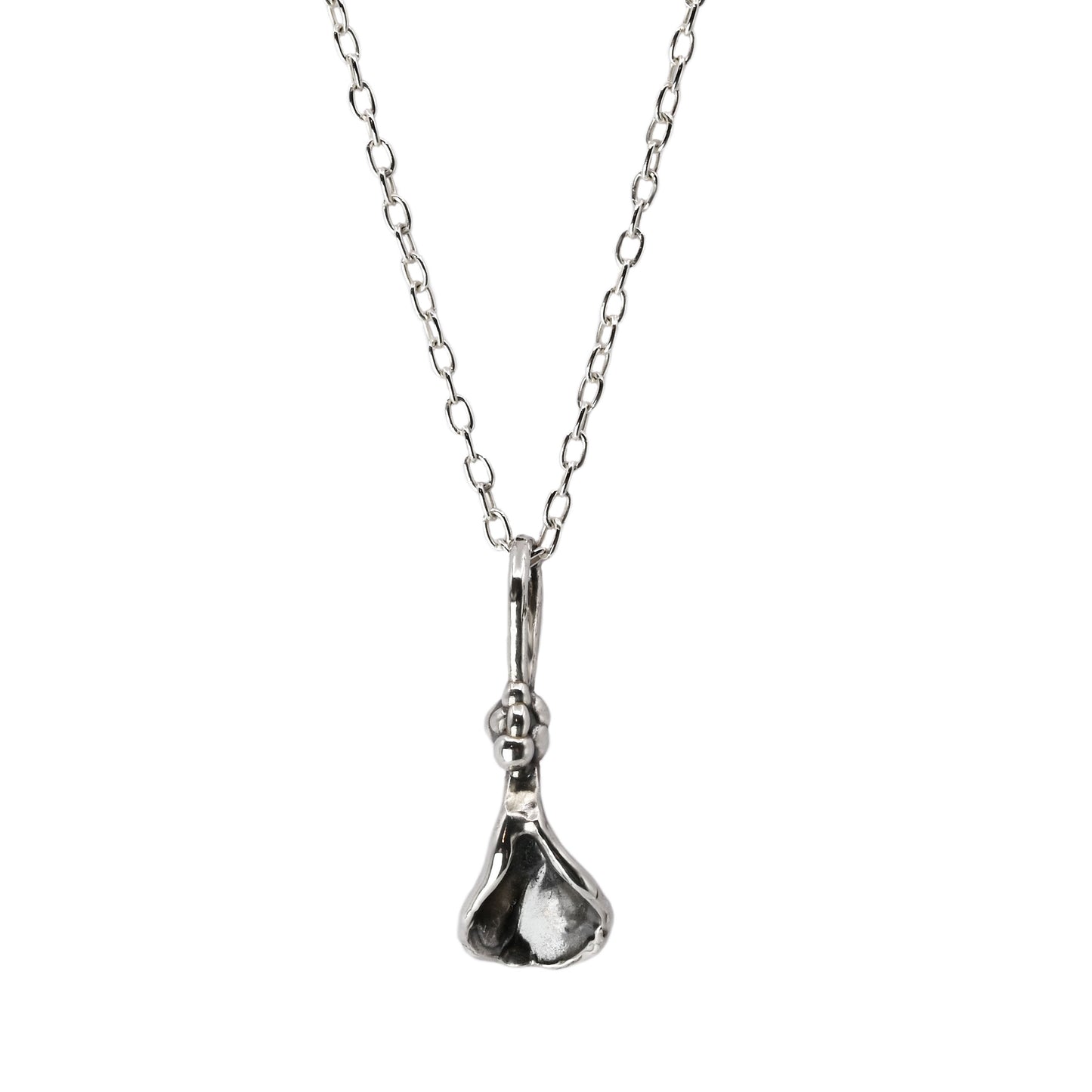 Frida Necklace with a small sterling silver pendant in a semi-abstract vulva shape, accented with small bead-like details, hanging on a delicate silver chain.
