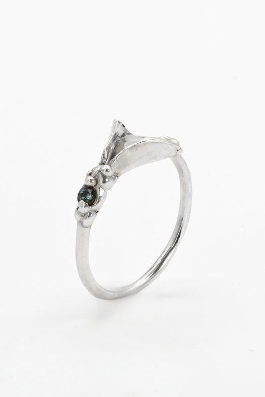 Silver impurity ring with a green gemstone on a white background
