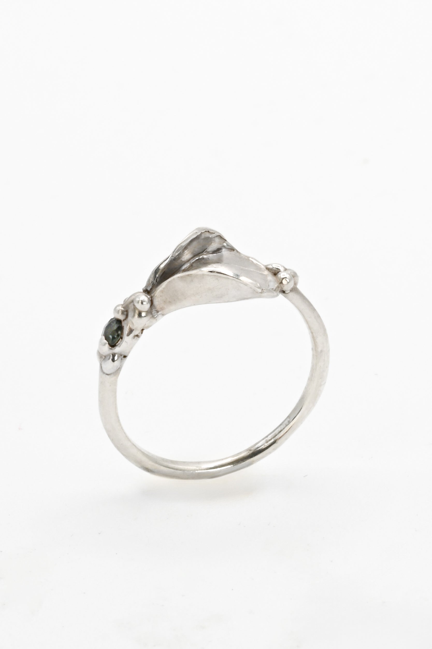 Top side view of a silver impurity ring with vulva design and teal blue sapphire by Impurity Culture Jewelry