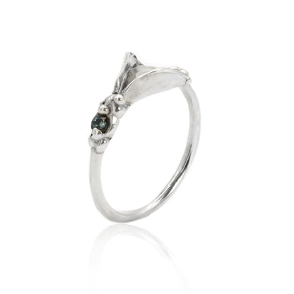 Silver vulva ring with a teal sapphire on a white background
