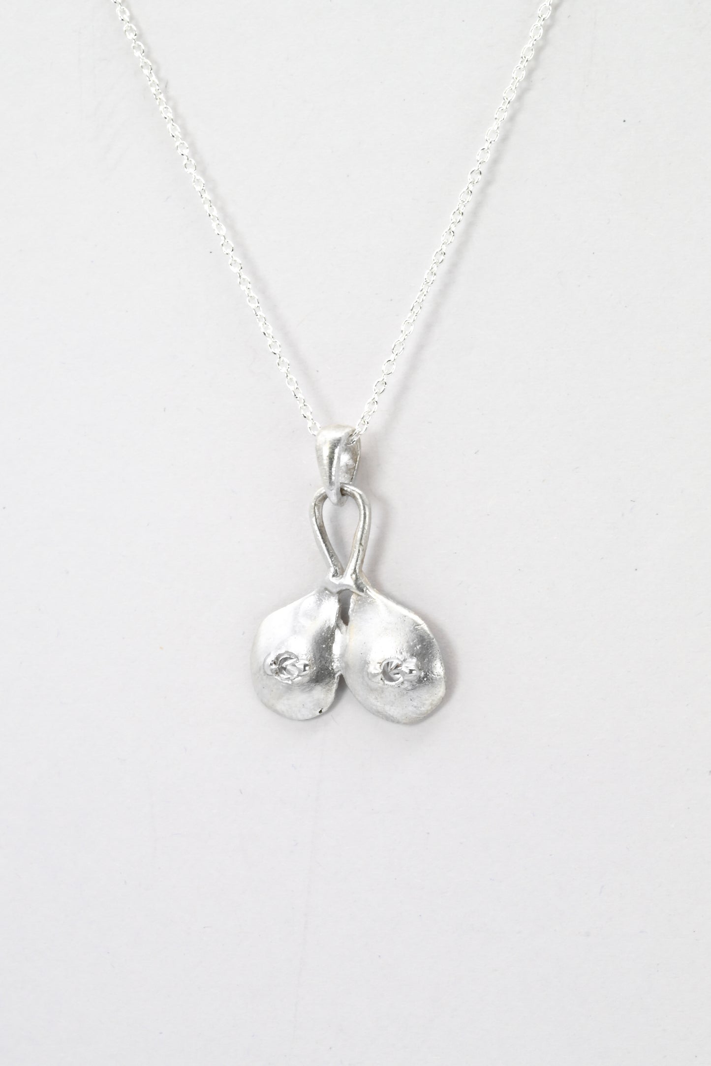 Profile view of "Godiva" silver breasts pendant with white sapphire nipples, by Impurity Culture Jewelry