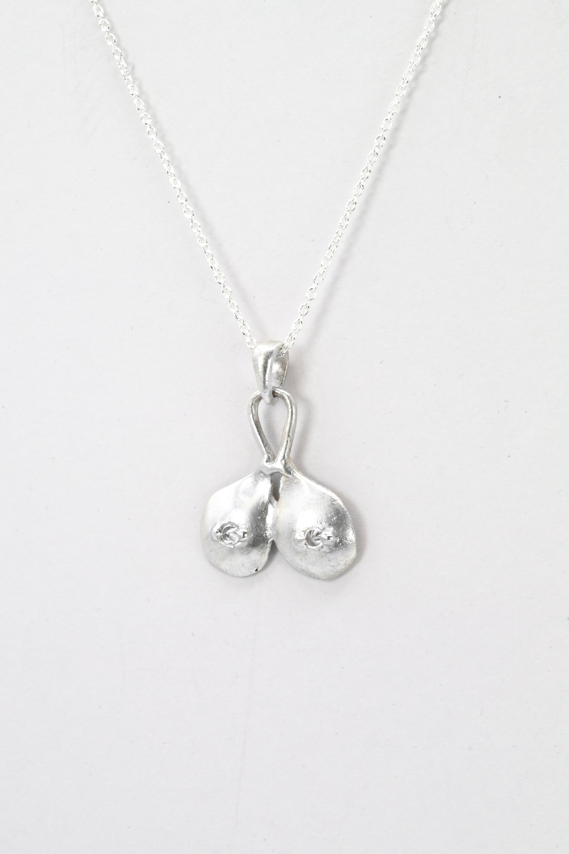 Profile view of "Godiva" silver breasts pendant with white sapphire nipples, by Impurity Culture Jewelry