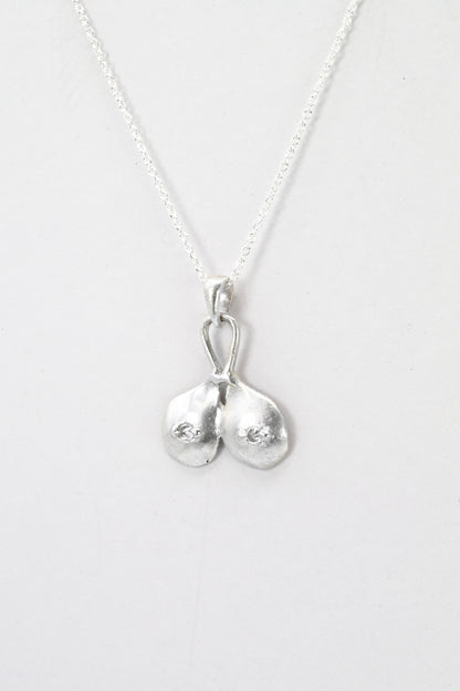 Profile view of "Godiva" silver breasts pendant with white sapphire nipples, by Impurity Culture Jewelry