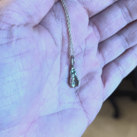 Tiny sterling silver vulva pendant with light blue sapphire. Handcrafted feminist jewelry by Impurity Culture.