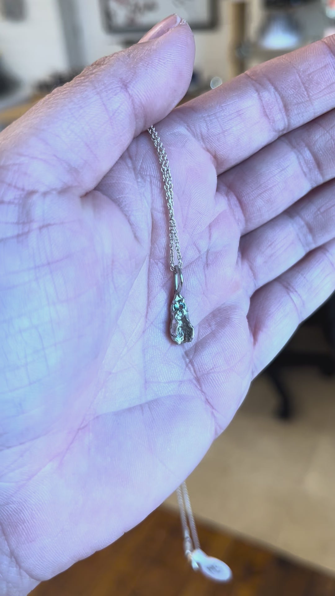 Tiny sterling silver vulva pendant with light blue sapphire. Handcrafted feminist jewelry by Impurity Culture.