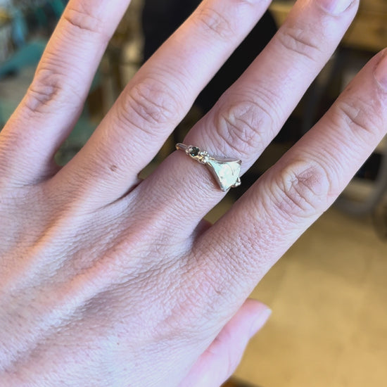 Sterling silver vulva ring with a teal sapphire modeled on a white woman's hand by Impurity Culture jewelry