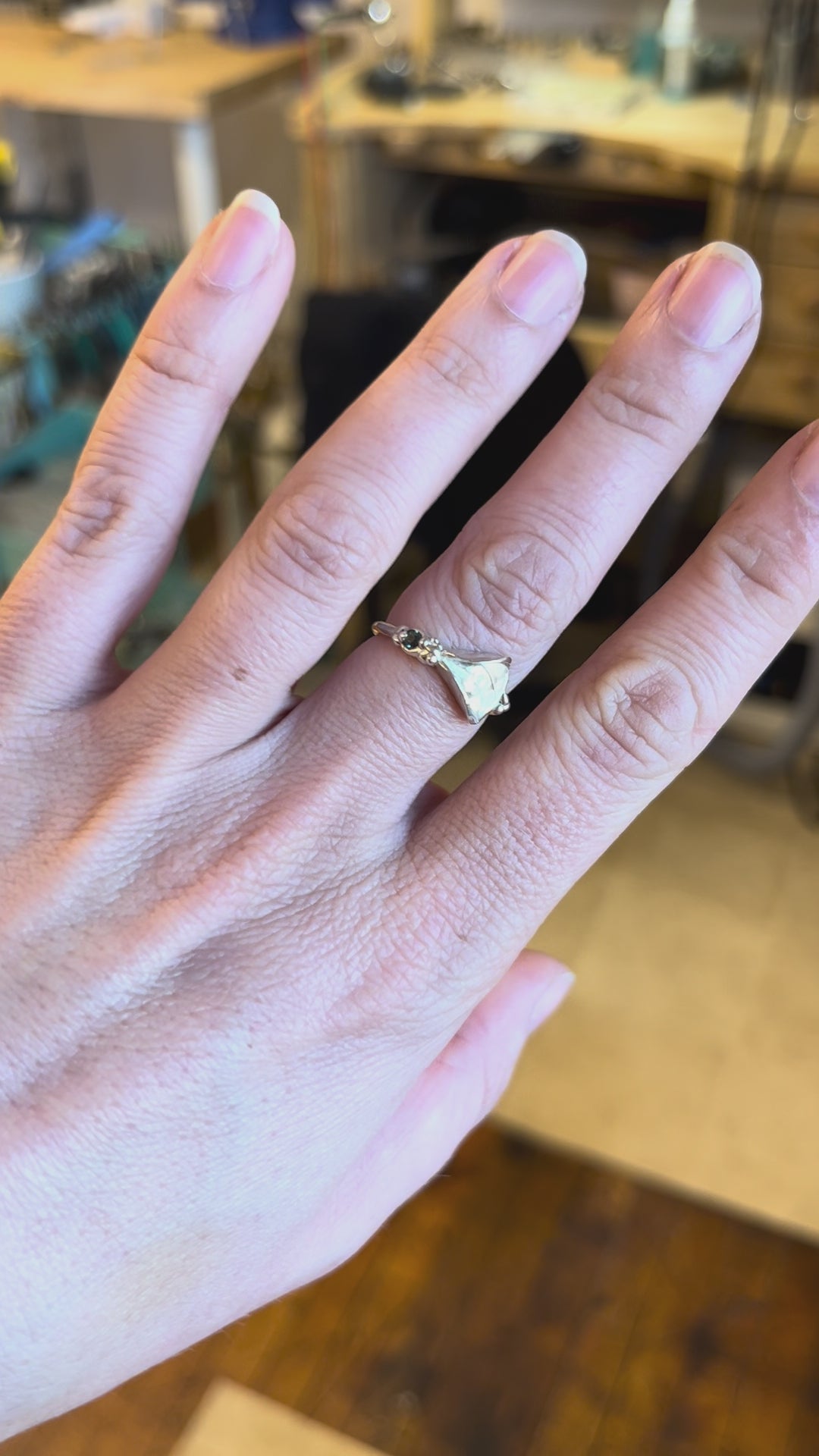 Sterling silver vulva ring with a teal sapphire modeled on a white woman's hand by Impurity Culture jewelry